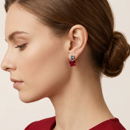 Close-up of a woman wearing a red earring with a blue gemstone on a beige background