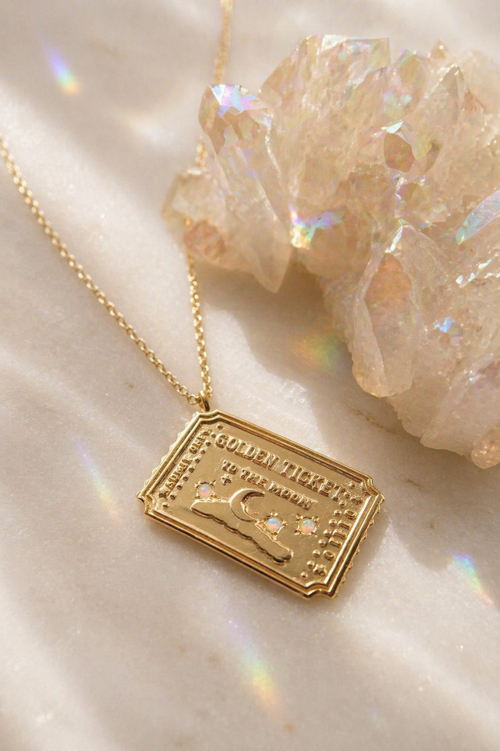 Gold ticket to the moon necklace with a rectangular pendant on a light background with crystals