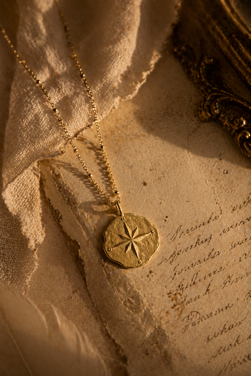 Gold necklace with a compass and star-shaped pendant on a textured surface